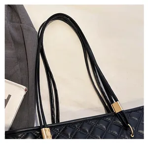 Close-up of black quilted tote bag with four slim straps and golden metal hardware details