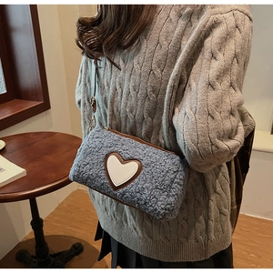 Détail du sac bandoulière en polaire grise avec écusson cœur blanc et texture douce