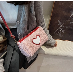 Détail du sac bandoulière en peluche rose avec patch cœur rouge et finitions dorées