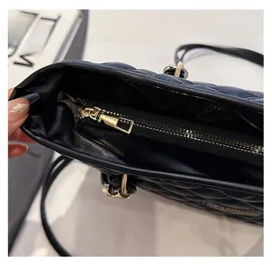Detail of smooth gold zipper and diamond quilted leather texture on a black tote bag
