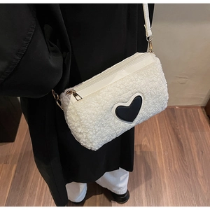 Détail du sac cylindre en laine d'agneau blanche avec patch cœur noir et zip doré chic