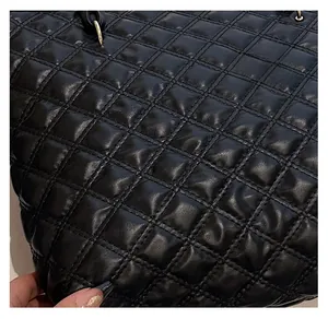 Close-up of black quilted tote bag texture with elegant gold ring hardware details