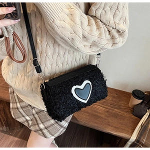 Sac bandoulière tendance en fourrure noire avec détail cœur porté en style automnal