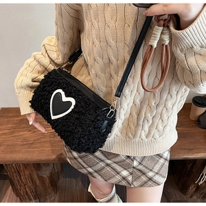 Détail du sac bandoulière en peluche noire avec motif cœur et texture douce en fausse fourrure