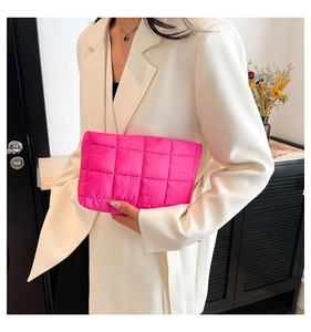 Detail van de roze gewatteerde clutch met kettingriem gedragen door een model in pak