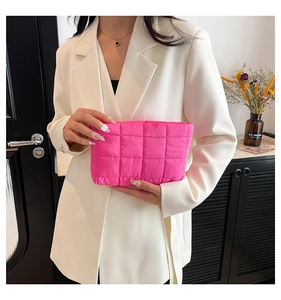 Macro-opname van de levendige fuchsia gewatteerde nylon make-uptas gedragen door model