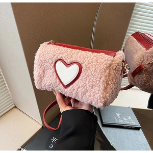 Détail macro du sac cylindre en peluche rose avec texture douce et écusson coeur