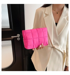 Detail van trendy neonroze gewatteerde tas met glanzende textuur vastgehouden door een model
