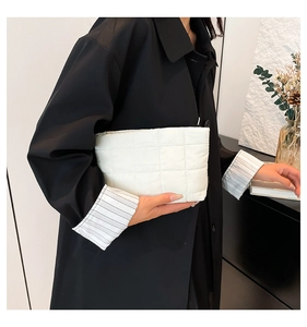 Detailopname van witte gewatteerde handtas met vierkant patroon gedragen door een model