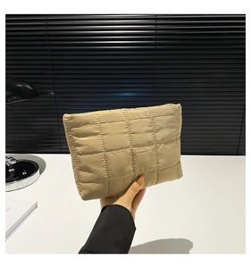 Detail van de beige gewatteerde cosmetische tas met een trendy geblokte textuur