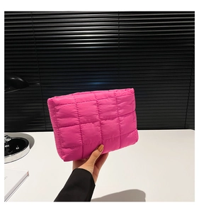 Detail van roze gewatteerde clutch met glanzende afwerking en trendy gevoerde textuur