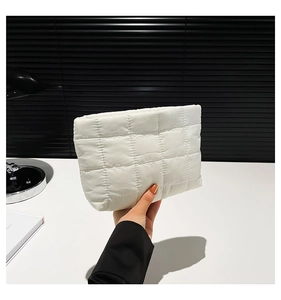 Detailweergave van de witte gewatteerde puffer-clutch met vierkant textuurpatroon
