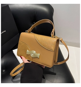 Detail of tan square handbag with smooth and crocodile pattern leather stitching