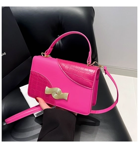 Detail of fuchsia leather handbag with gold wave-shaped metal buckle and crocodile texture