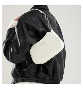 Detail of a white crescent shoulder bag with silver chain strap and fashion logo