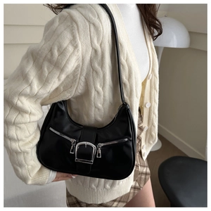 Détail du sac à bandoulière noir en forme de croissant avec boucle et zip métalliques