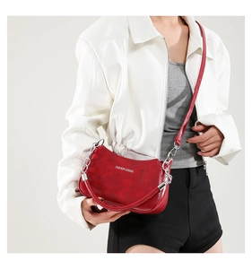 Detail of red wrinkled patent leather crescent bag with silver chain strap and logo