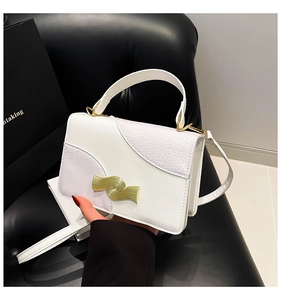 Detail of white leather small square bag showing croc-embossed texture and gold metal clasp