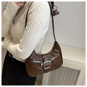Gros plan d'un sac demi-lune marron foncé avec boucles argentées et zips décoratifs