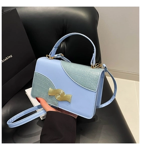 Detail of light blue square handbag with green crocodile pattern and wave metal lock