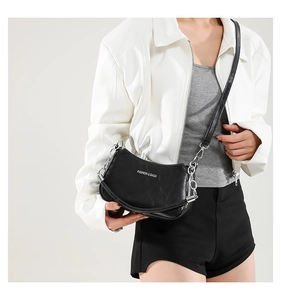 Detail of black crescent shoulder bag featuring silver chain strap and fashion text print