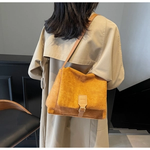 Detail of ginger yellow matte leather crossbody bag with metal buckle on model