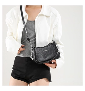 Close-up of black pleated PU leather crescent bag with silver chain and metal zipper