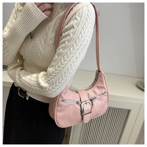 Sac hobo rose porté à l'épaule sur un pull en maille torsadée de couleur crème