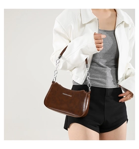 Detail of dark brown crescent bag with silver chain strap and fashion lettering print