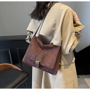 Detailed macro view of the brown suede surface and dark leather strap on a rectangle bag