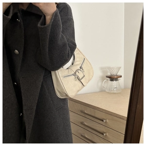 Détail du sac croissant en cuir blanc cassé avec boucles argentées et doubles fermetures