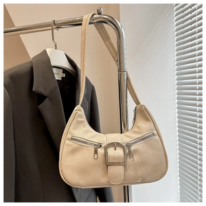 Détail du sac hobo beige avec large boucle et fermetures éclair sur un cintre en métal