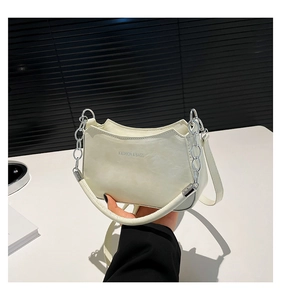Detail of white crescent bag with silver chain and Fashion & Bags text on glossy surface