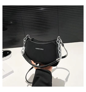 Detail of black crescent moon shoulder bag with silver chain and white fashion logo