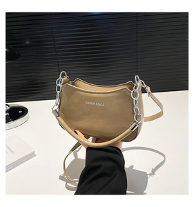 Detail of khaki crescent shoulder bag with silver chain and Fashion & Bags text on desk