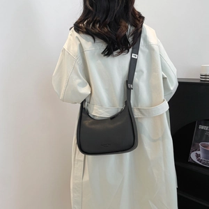 Minimalist black crescent crossbody bag in matte faux leather worn by a model