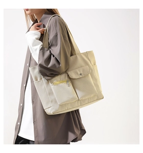 Detailansicht der großen beigen Canvas-Tragetasche mit funktionellen Taschen und Gurt