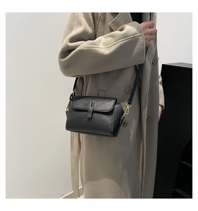 Sac bandoulière classique en cuir noir à texture litchi porté par un mannequin