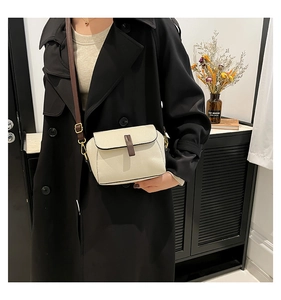 Détail du sac carré en cuir grainé blanc cassé avec bandoulière marron et boucles dorées