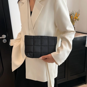 Stijlvolle zwarte gewatteerde cloud clutch met ruitstiksel bij een witte blazer