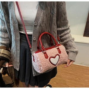 Detail of pink faux fur crossbody bag with red leather handles and heart decoration