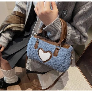 Blue cylinder fuzzy bag with white heart detail and brown leather strap on model