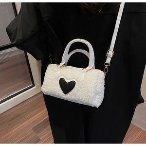 Detail of white plush cylinder bag with black leather heart and golden hardware