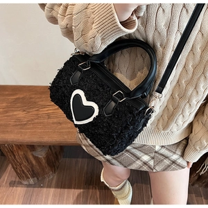 Macro detail of black fuzzy cylinder bag with heart design on model in warm setting