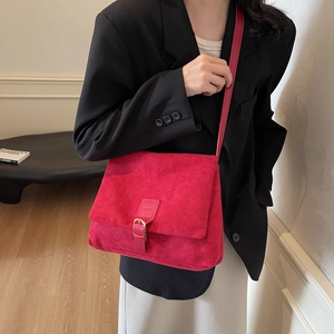 Minimalist red suede shoulder bag styled with black blazer in a modern studio