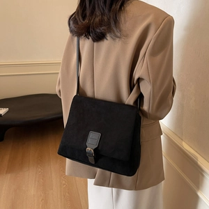 Retro black faux suede shoulder bag for women with flap buckle on a female model