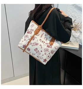 Detail view of large tote bag featuring artistic graffiti prints and brown leather handles
