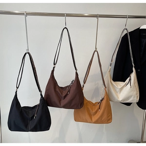 Sacs hobo en toile rétro noir, marron et beige suspendus sur un portant de mode