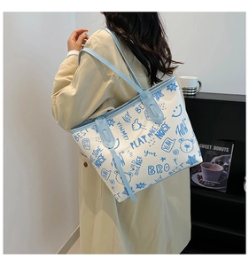 Woman carrying large white tote bag with blue graffiti patterns in a modern indoor setting