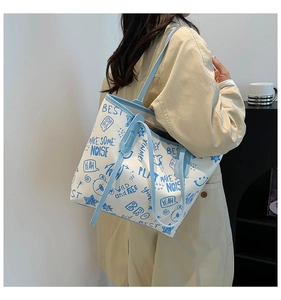 Détail du sac cabas blanc avec lettrage graffiti bleu et bandoulières en cuir bleu